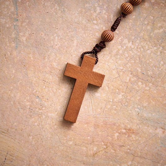 Pleciony różaniec z ciemnego sznurka z imitacji drewna z zawieszką w kształcie krzyża: symbol mało wymagającej ozdoby religijnej